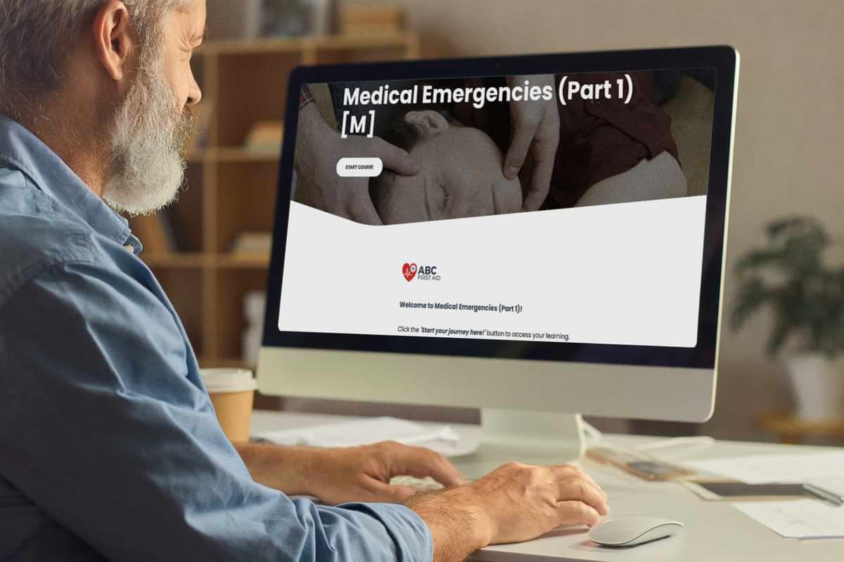 A person sitting at a desktop computer, with the Medical Emergencies topic showing from the First Aid Awareness Course