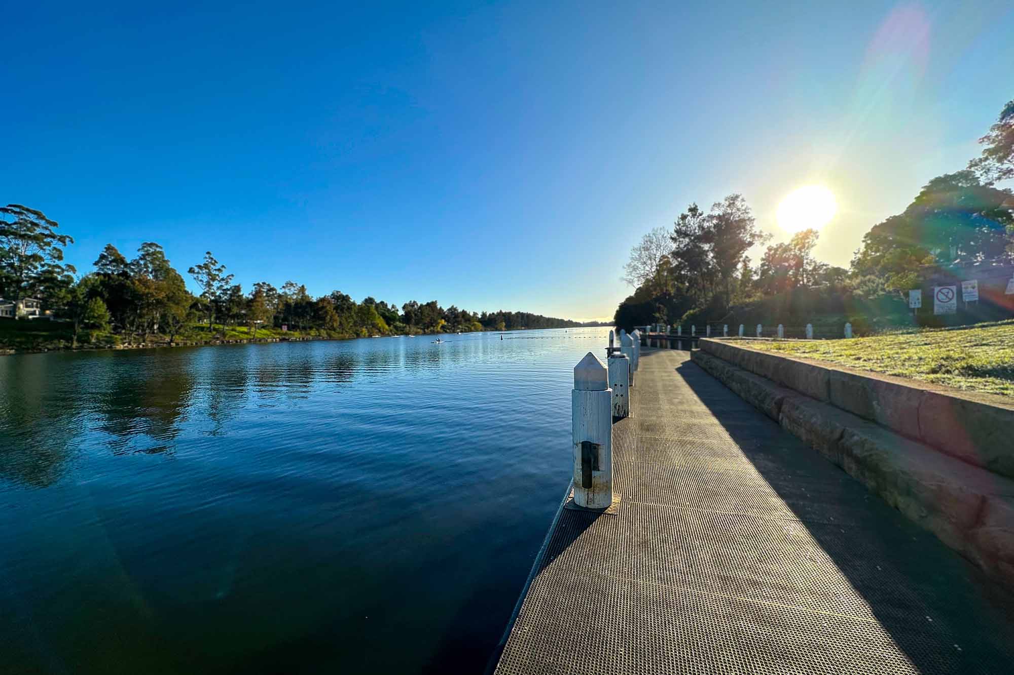 The Nepean River in Penrith in early morning, with the sun rising over the banks, and kayakers on the water